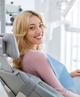 Blonde female dental patient sitting in chair and smiling