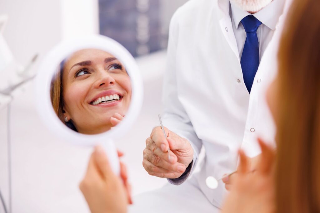 A woman looking in the mirror at the dentist's office.